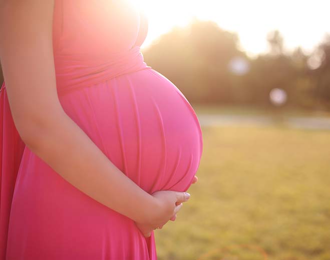 pregnant woman holding belly in the sun